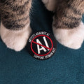 Black pin badge that reads 'ARTISTS AGAINST AI' and 'SUPPORT HUMAN ART' with a red AI symbol crossed out.
