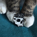 White skull-shaped pin with cat silhouettes.