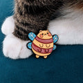 Chubby bee pin with a cat face, resting on the paw of mito.