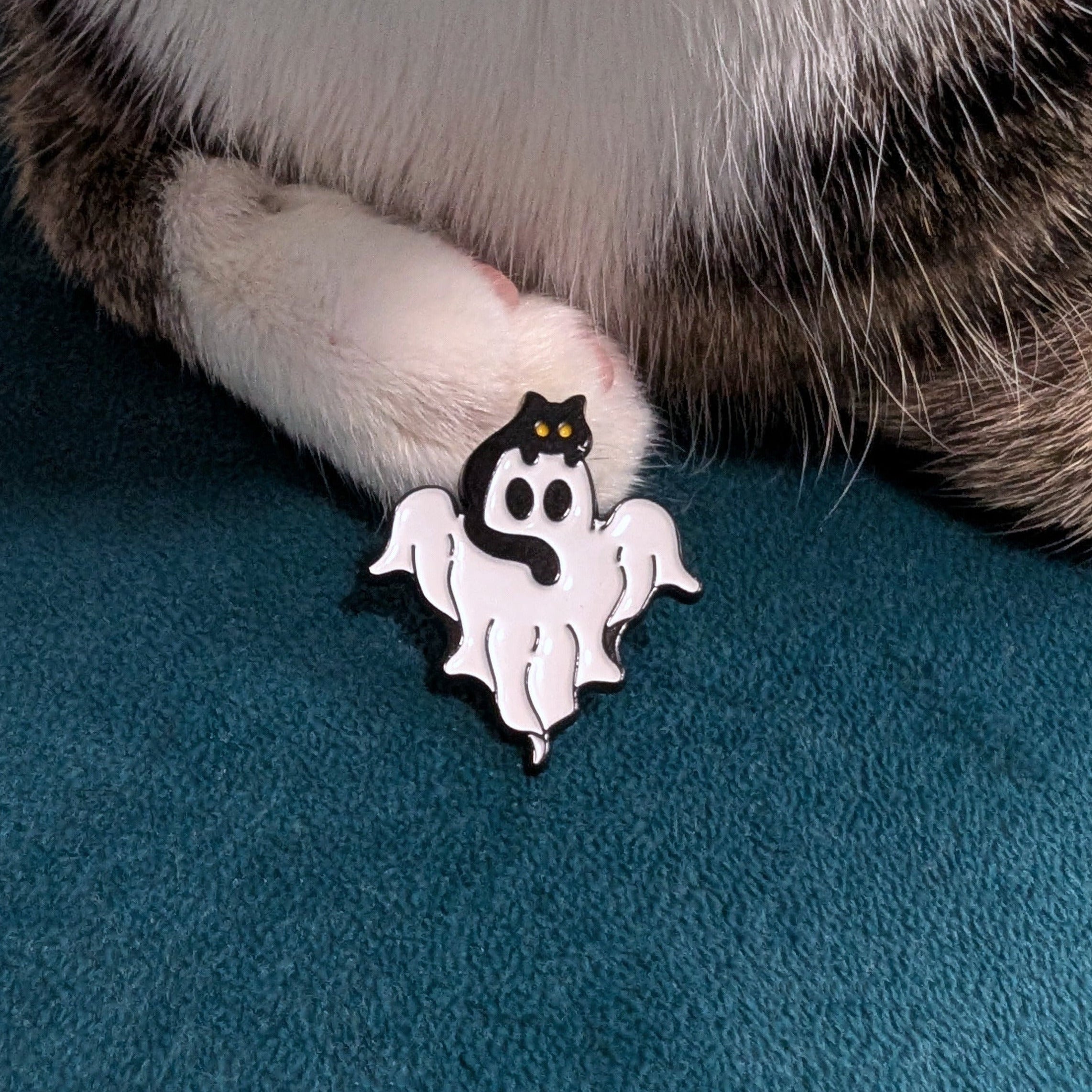 Small white ghost-shaped enamel pin featuring a black cat on top.