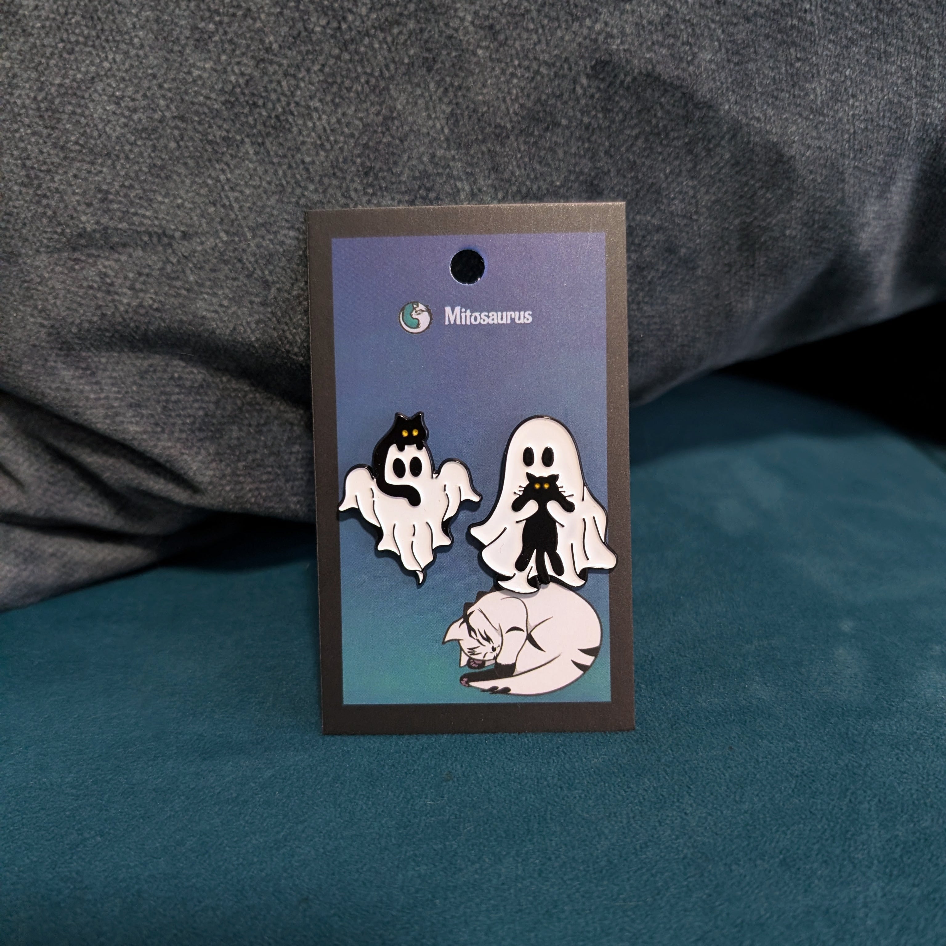 Ghost and cat enamel pin with two designs: a ghost cuddling a cat and a cat riding a ghost